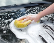 Female hand with yellow sponge washing car