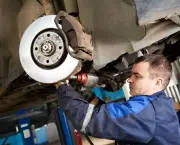 car mechanic examining car suspension of lifted automobile at repair service station