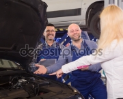Woman shows mechanic a problem with car