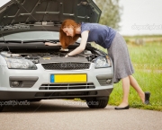 Woman fixing her car on the road